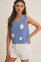 Woman wearing a blue knit top with white flower appliques on a beige background