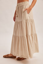 Woman wearing a natural tiered striped skirt with embroidered cutout on a plain background