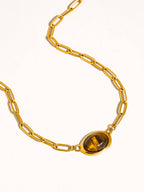 Gold plated paper clip chain necklace with a cat's eye stone on a white background