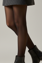 A model's lower body wearing a dark gray textured A-line skirt, sheer black tights, and black leather ankle boots against a white studio background.