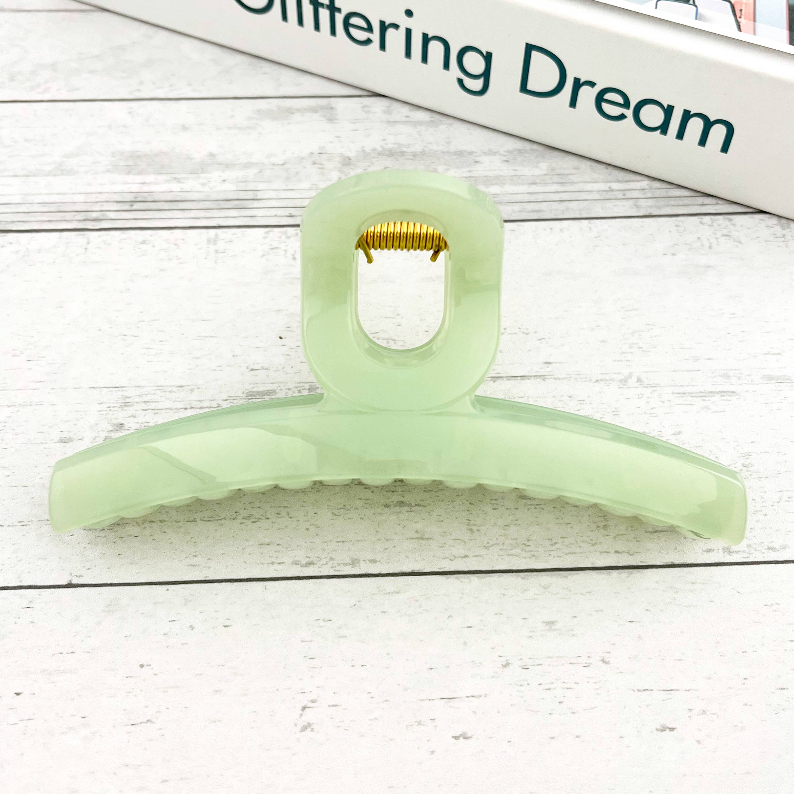 Light green hair claw on a white wooden 