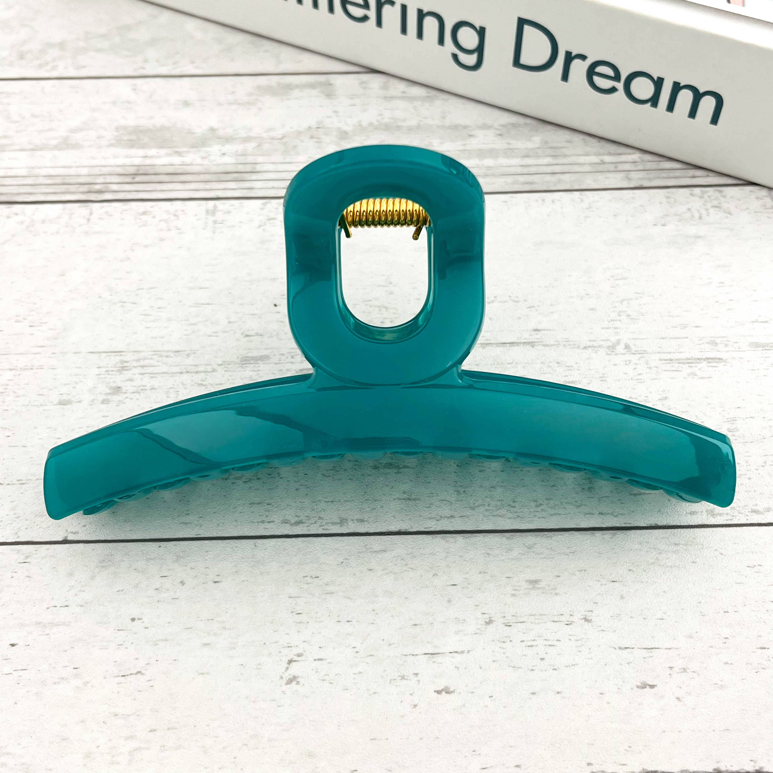 Teal hair claw on a light wooden surface 