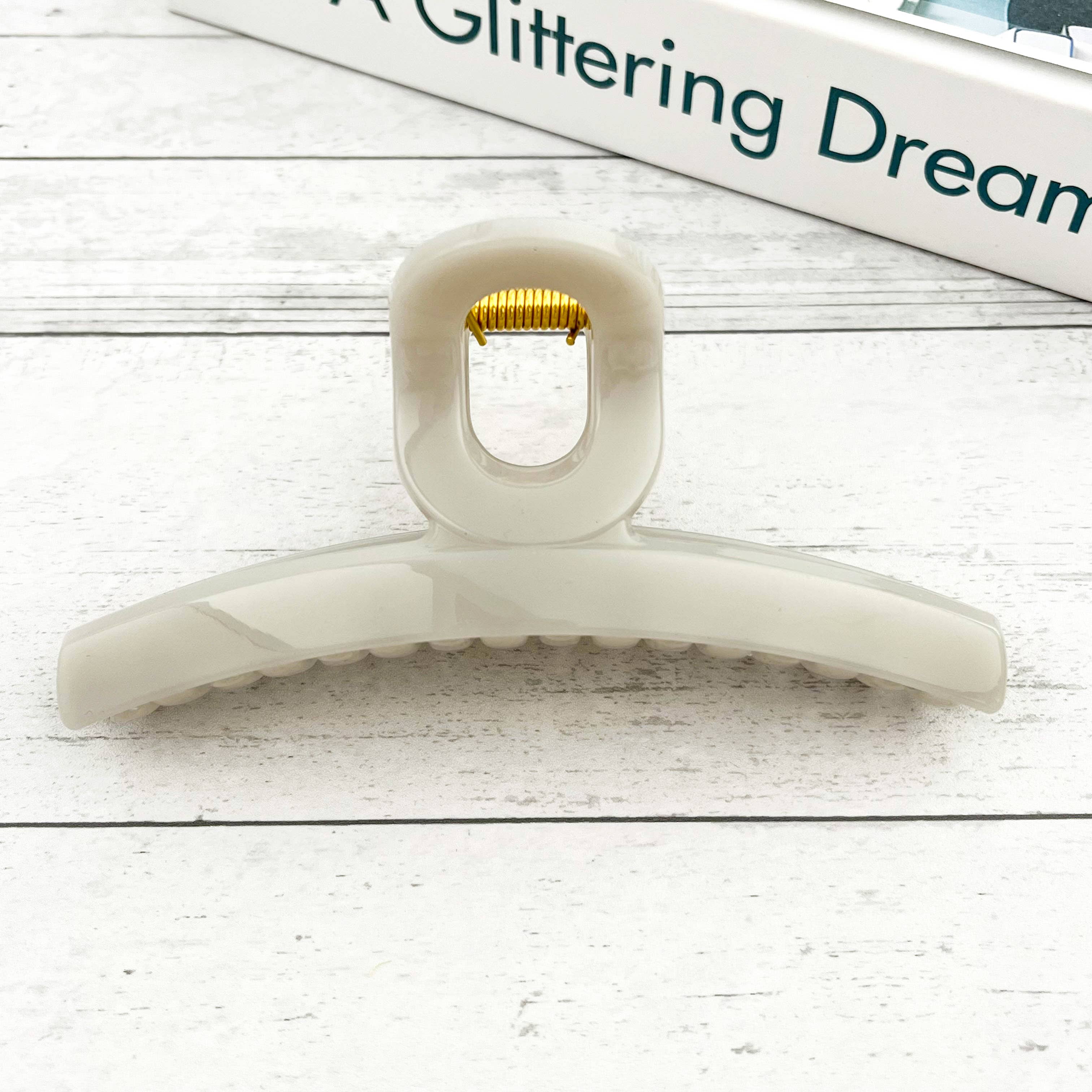 Clear hair clip with gold clip on a light wooden surface