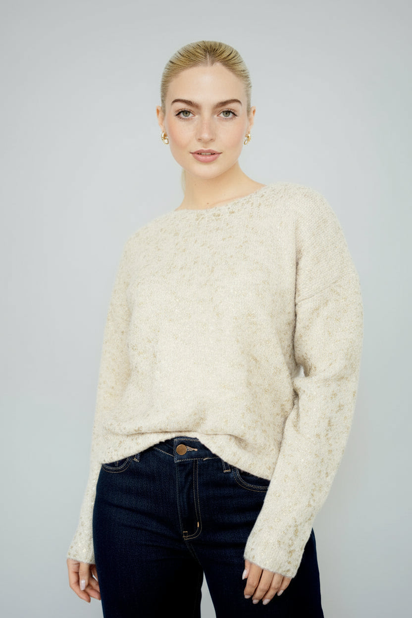 Woman wearing a gold foil speckled ecru knit sweater against a white background
