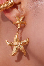 Woman wearing gold starfish dangle earrings
