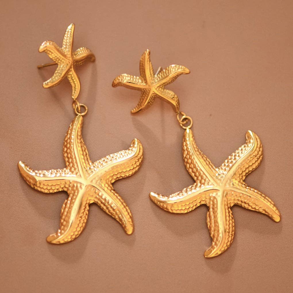 Gold starfish earrings on a brown background