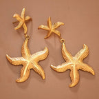 Gold starfish earrings on a brown background