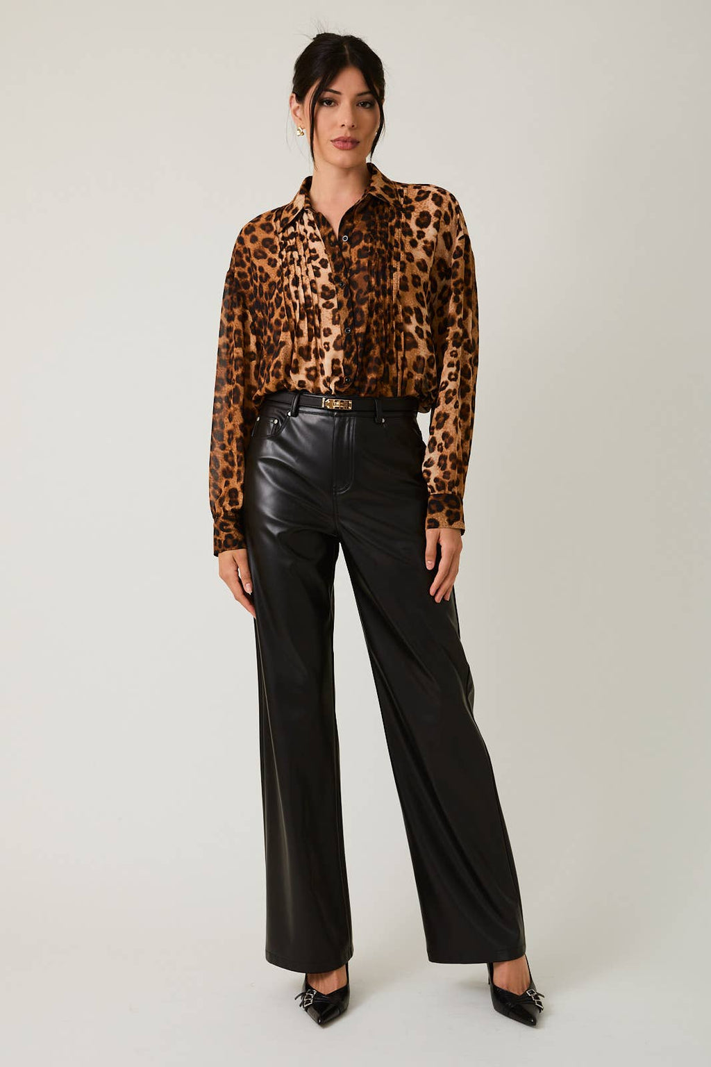Woman wearing a leopard print shirt and black pants on a white background