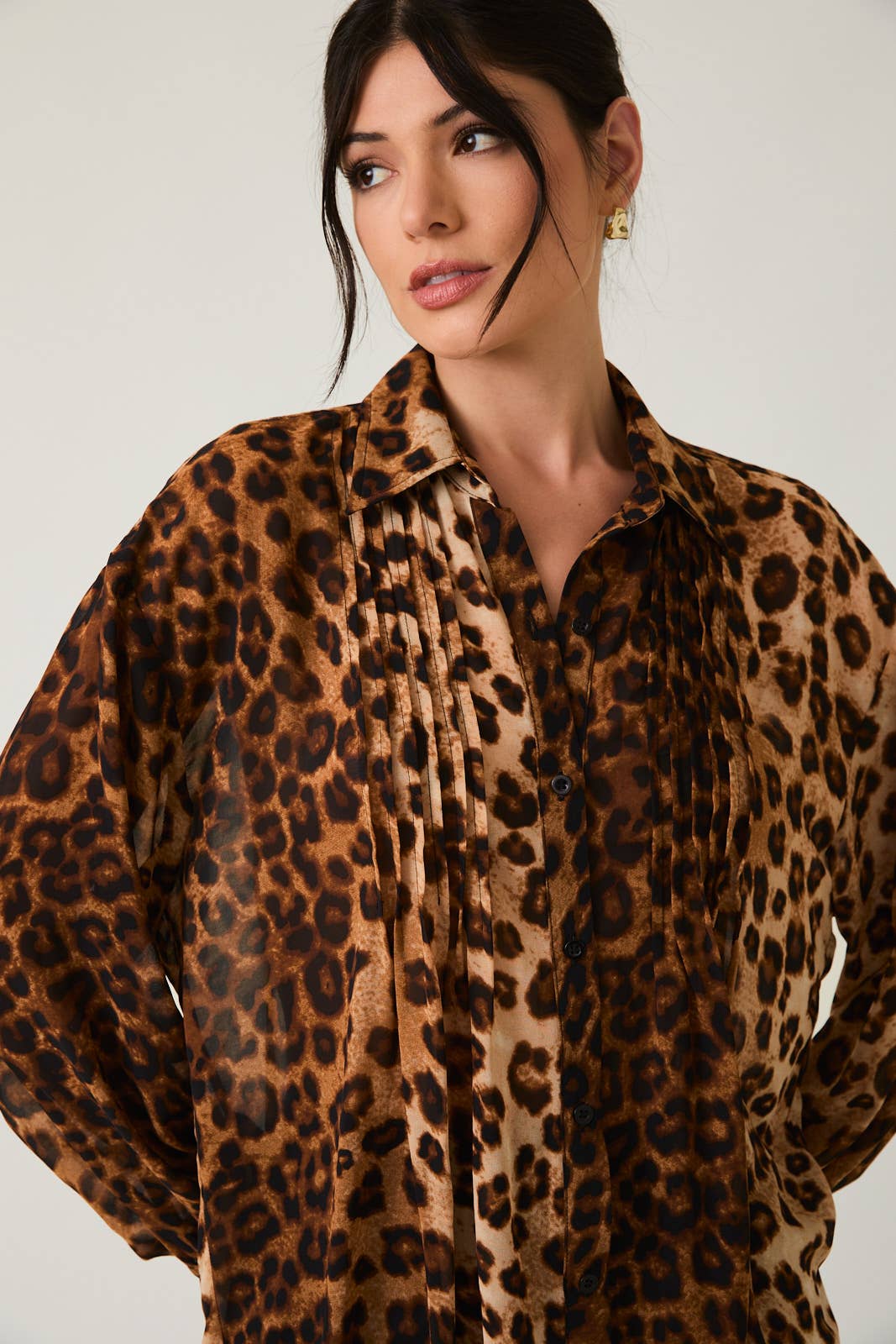 Woman wearing a leopard print shirt against a plain background