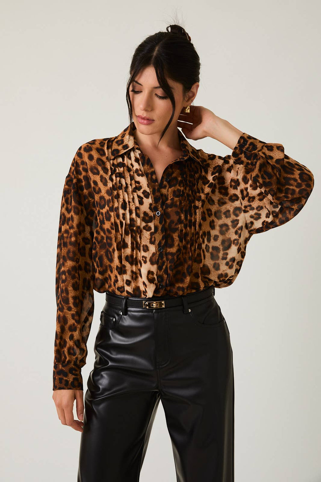 Woman wearing a leopard print blouse and black pants against a plain background