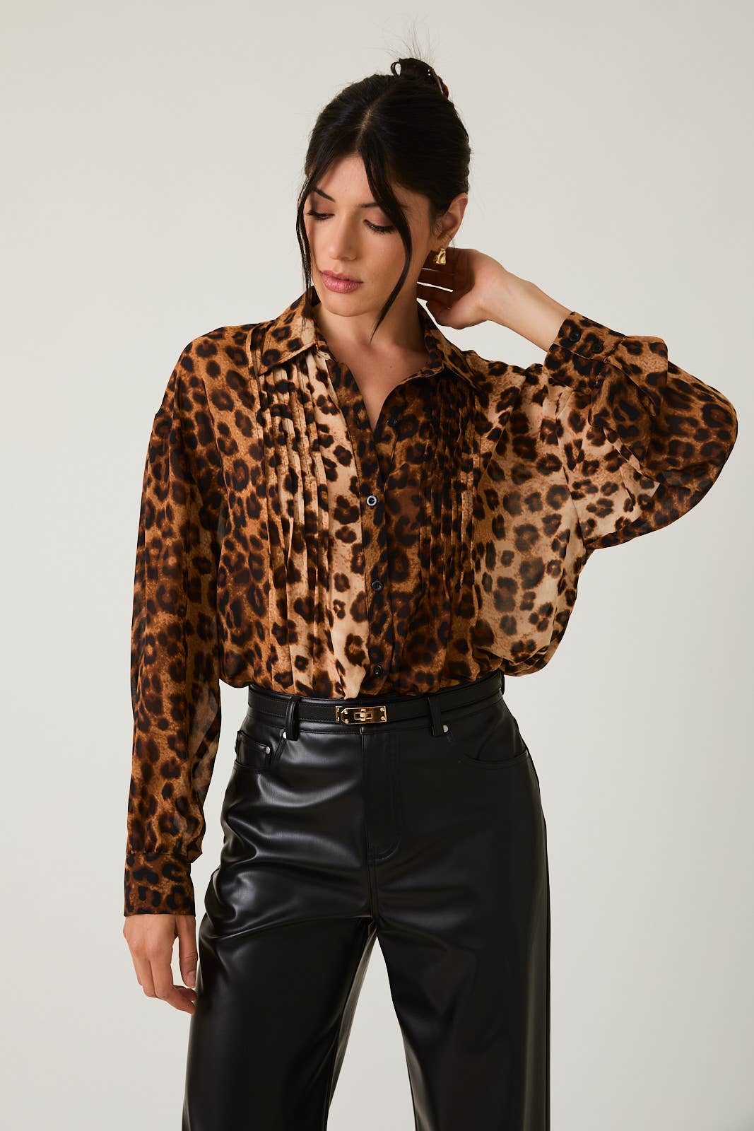 Woman wearing a leopard print blouse and black pants against a plain background
