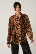 Woman wearing a leopard print shirt against a plain background