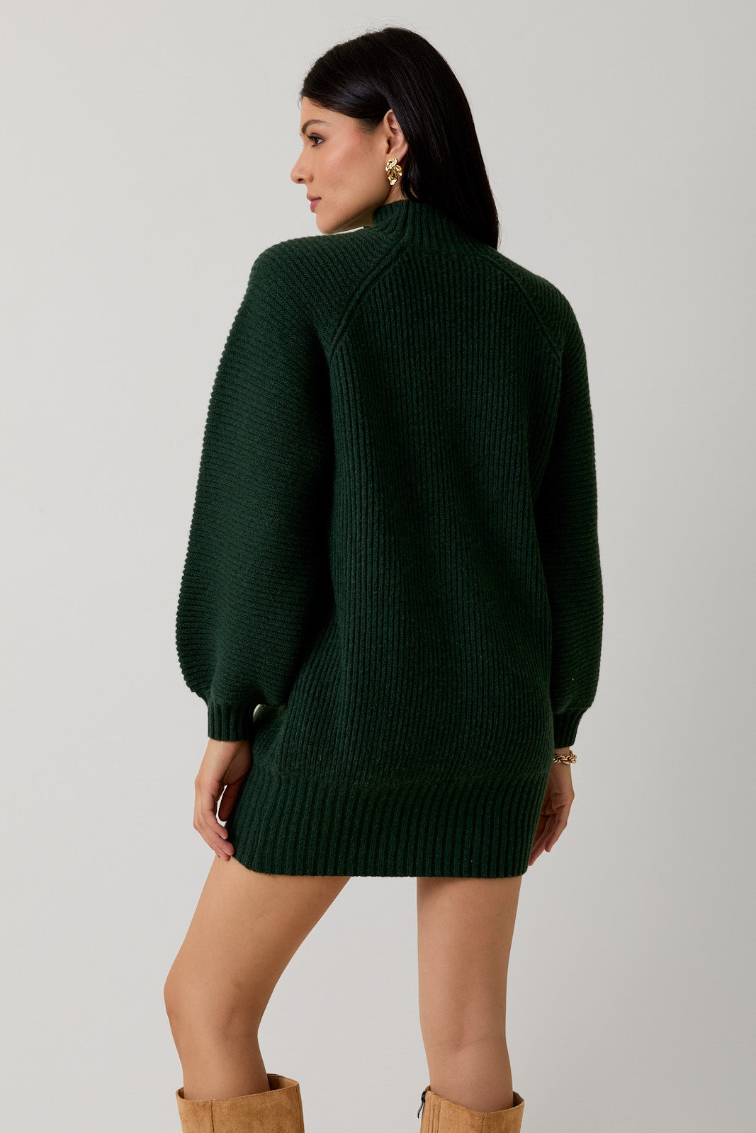 Back view of a woman wearing a hunter green sweater dress against a plain background