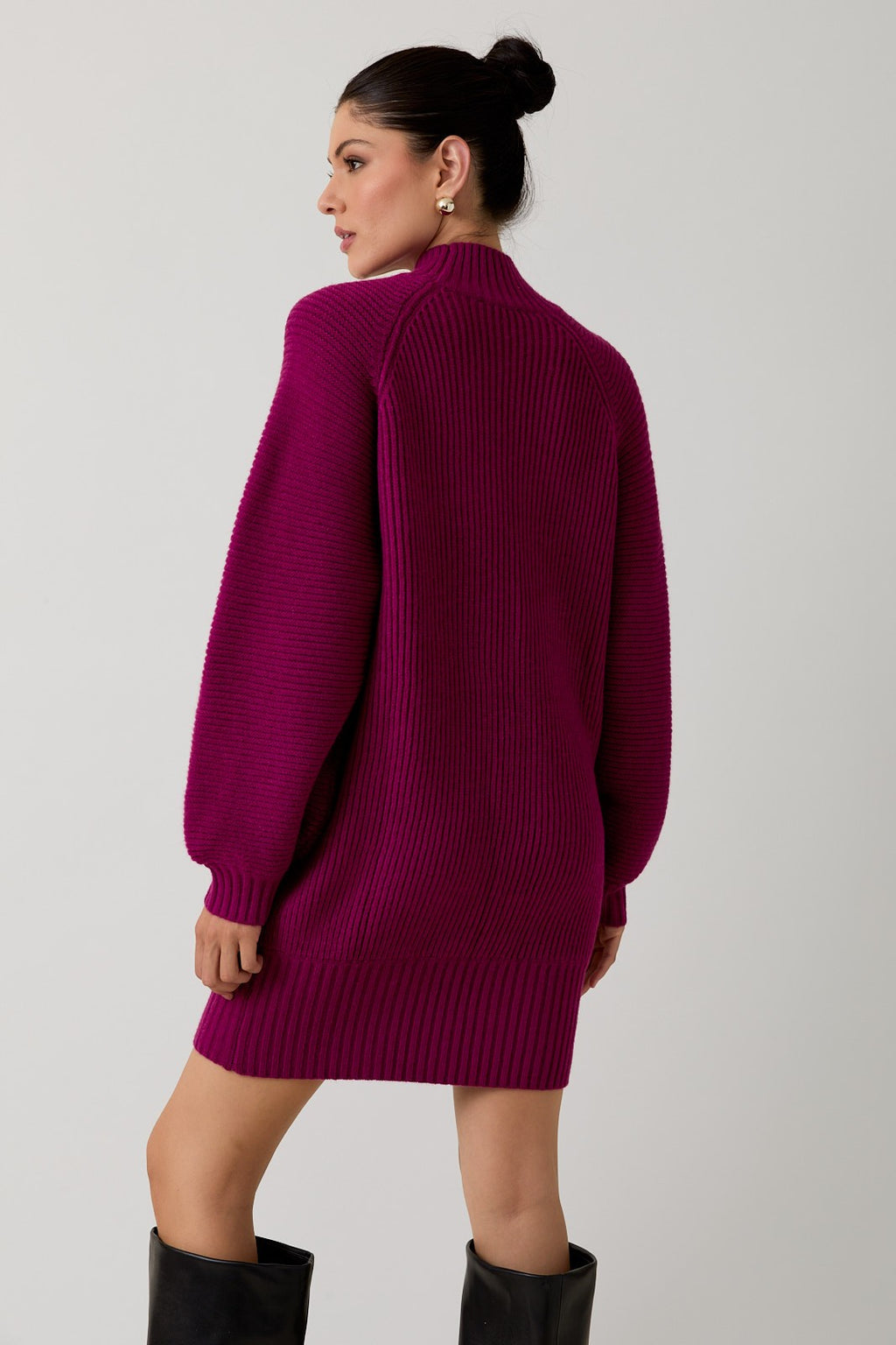 Back view of a woman wearing a magenta mock neck raglan balloon sleeve sweater dress against a plain background