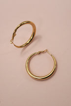 18k gold-plated puffy hoop earrings on a pink background