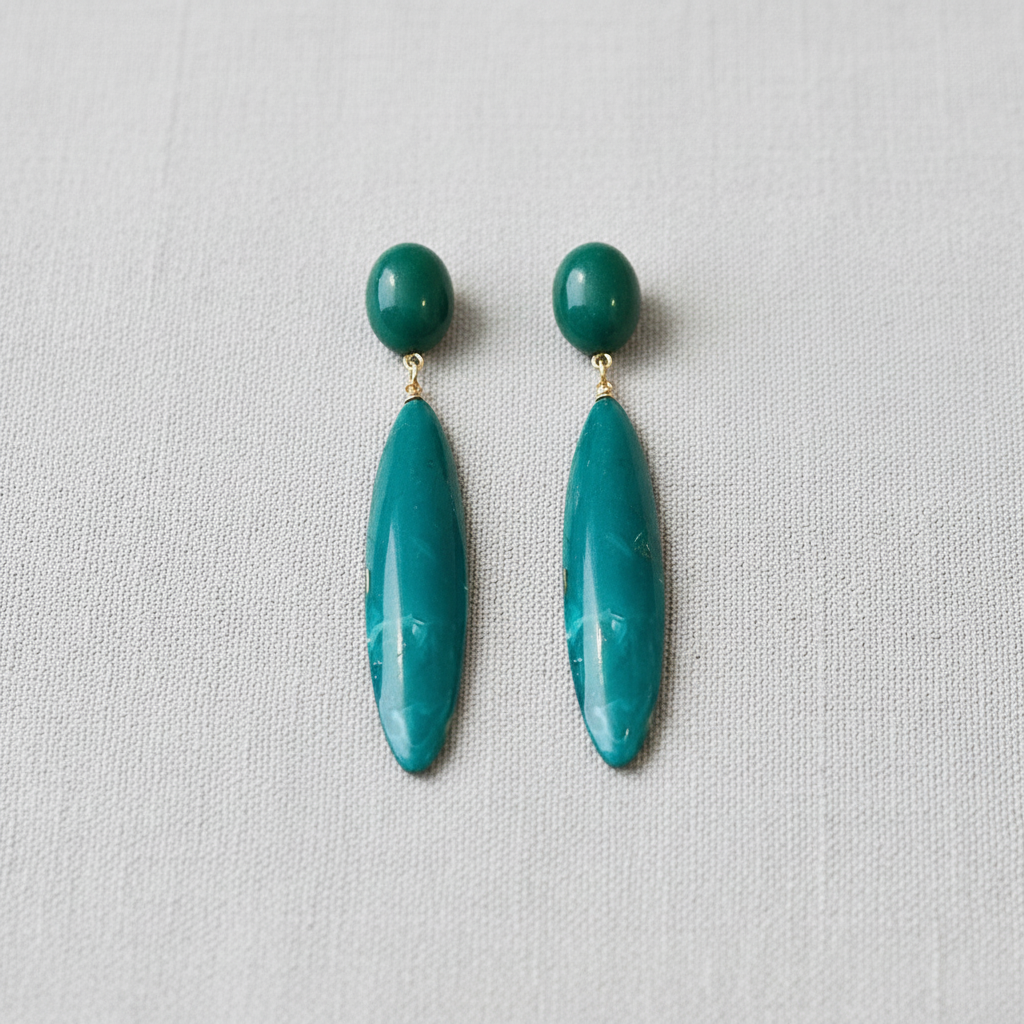 Pair of emerald green earrings on a light gray background
