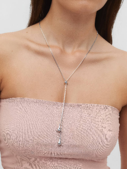 Woman wearing a silver-plated adjustable lariat style teardrop pendant necklace.