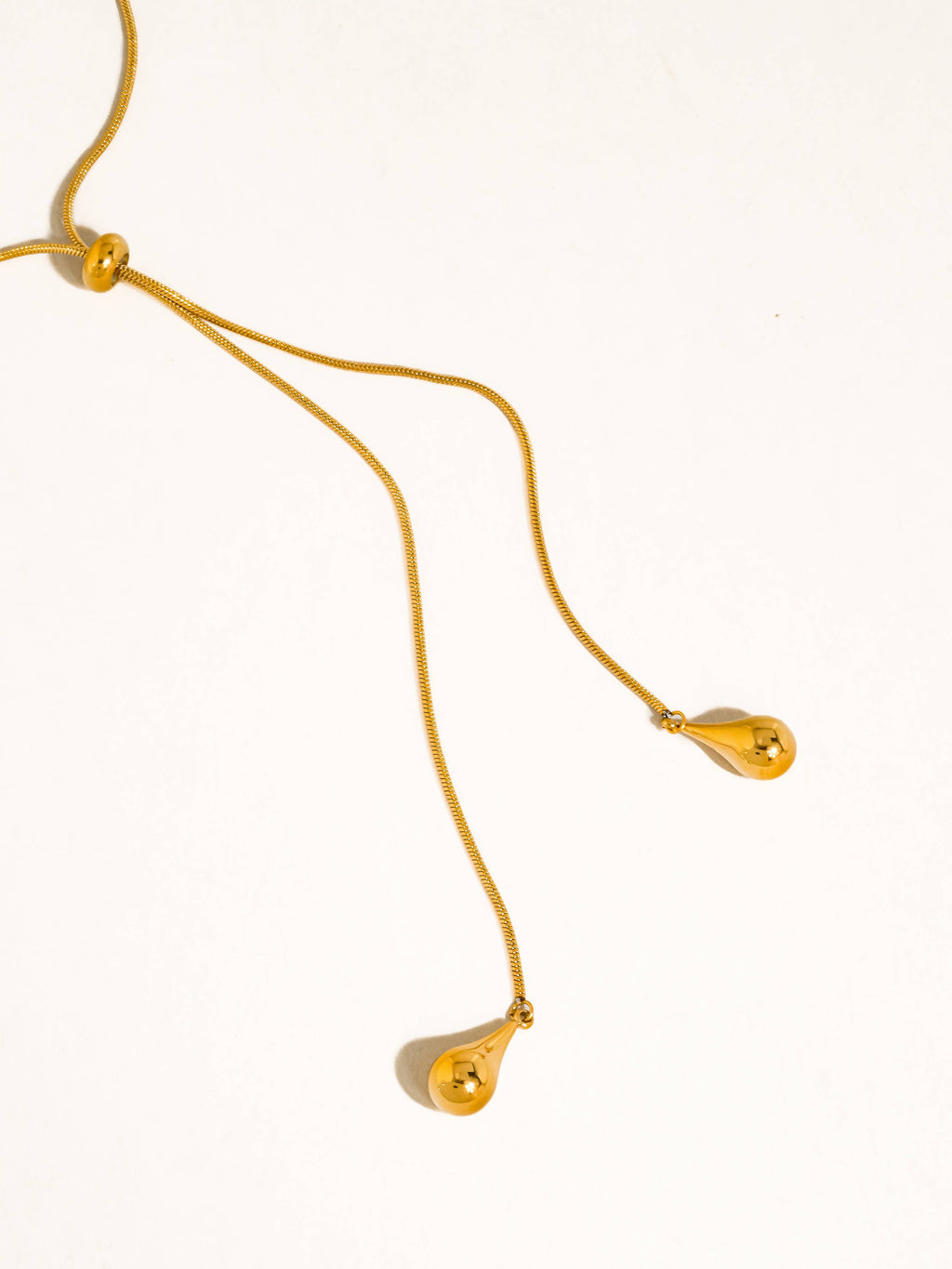 A delicate gold chain lariat drop necklace with teardrop pendants shown on a plain white background.