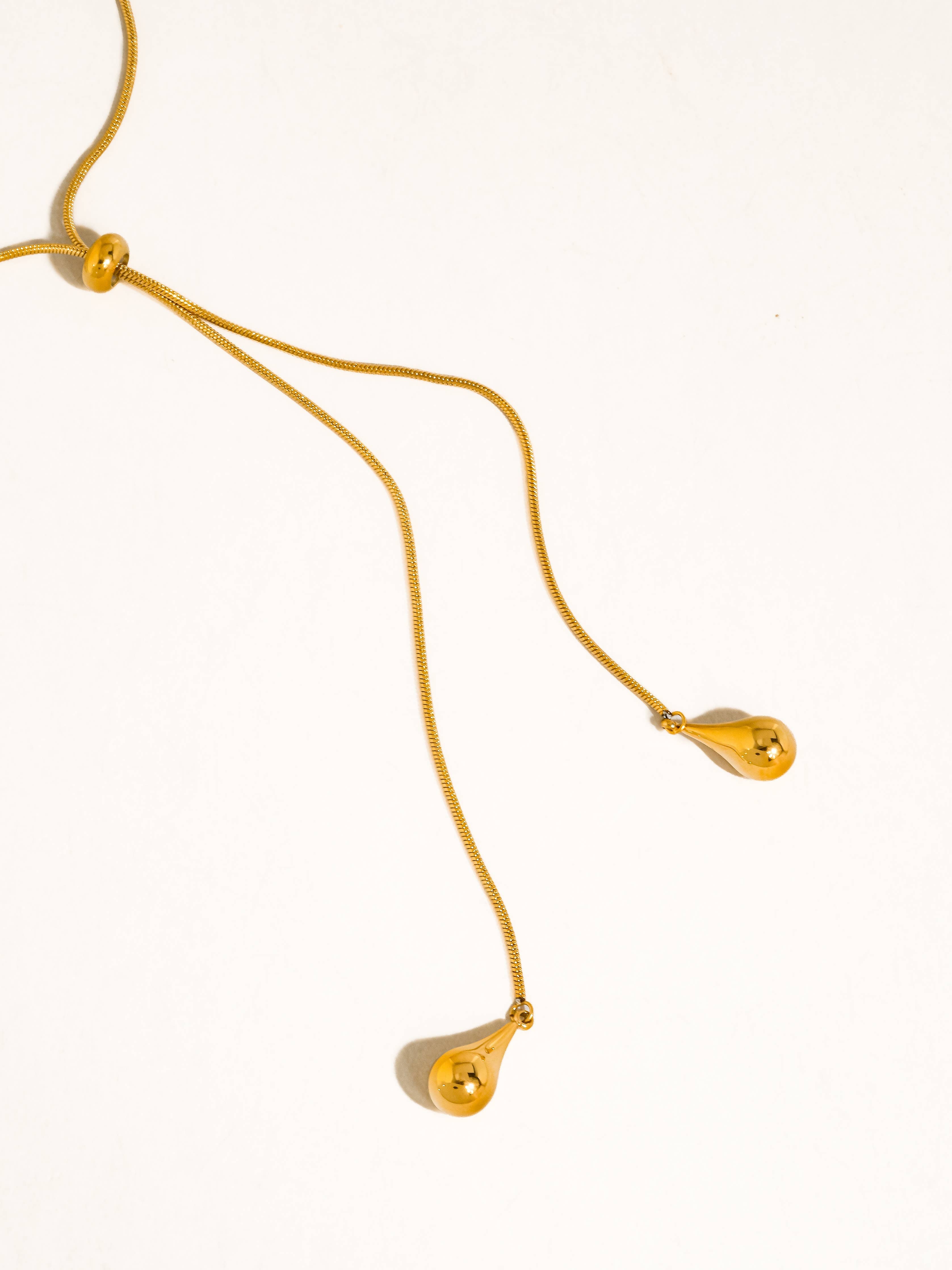 A delicate gold chain lariat drop necklace with teardrop pendants shown on a plain white background.
