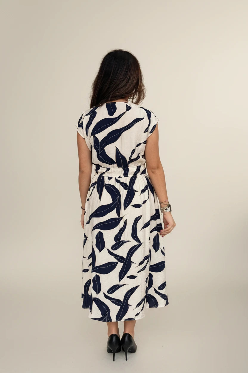 Woman wearing a white dress with navy leaf pattern on a white background