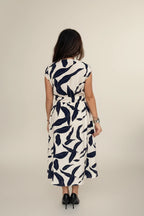 Woman wearing a white dress with navy leaf pattern on a white background