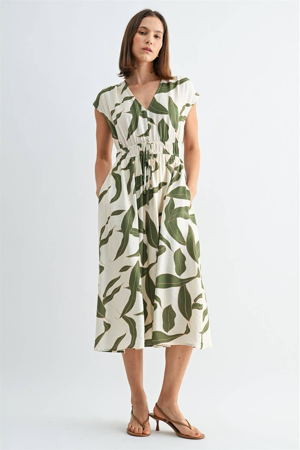 Woman wearing a green and white leaf-patterned dress on a white background