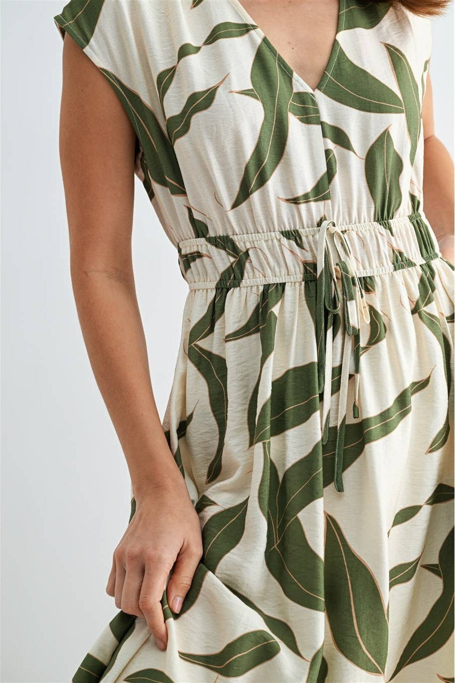 Woman wearing a green and white leaf-patterned dress on a white background