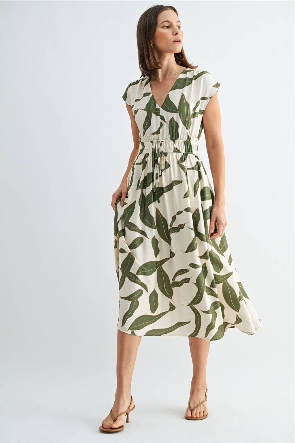 Woman wearing a green and white leaf-patterned dress on a white background