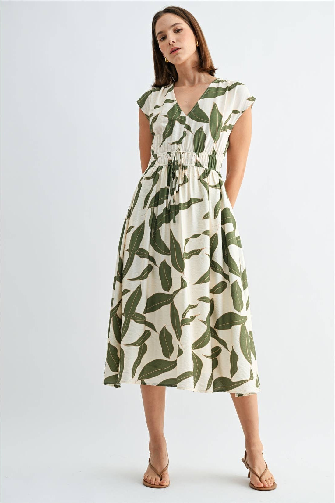 Woman wearing a green and white leaf-patterned dress on a white background