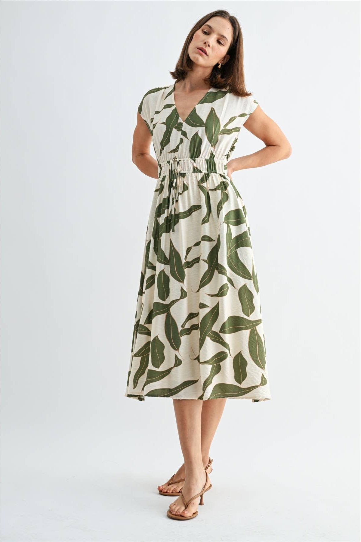 Woman wearing a green and white leaf-patterned dress on a white background