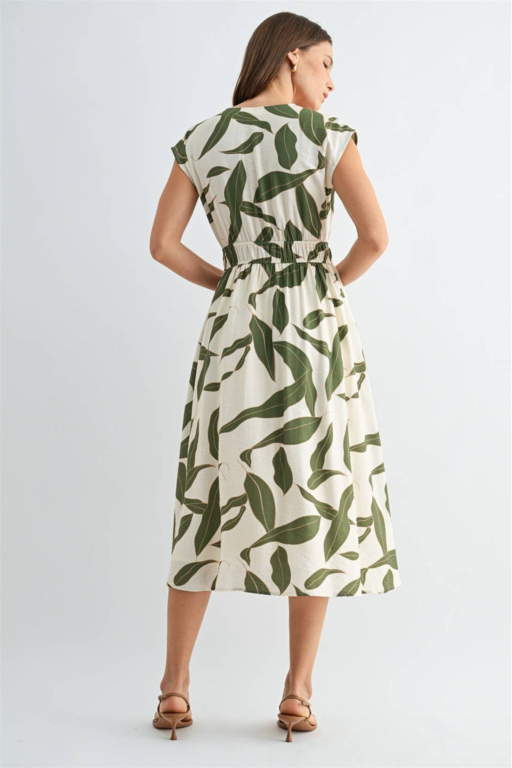 Back view of a woman wearing a green and white leaf-patterned dress on a white background