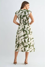 Back view of a woman wearing a green and white leaf-patterned dress on a white background