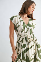 Woman wearing a green and white leaf-patterned dress on a white background
