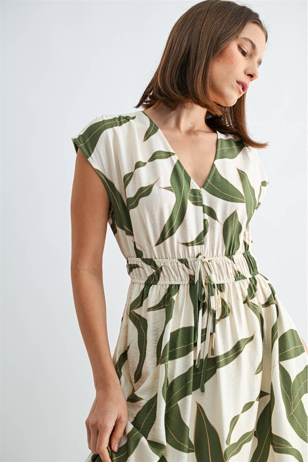 Woman wearing a green and white leaf-patterned dress on a white background
