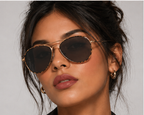 Woman wearing aviator sunglasses with a neutral background