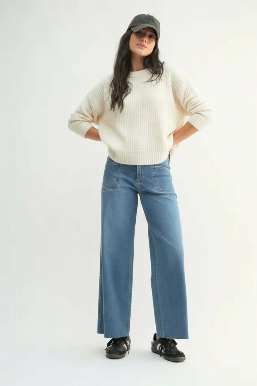 Woman wearing medium wash slim wide leg jeans and a sweatshirt and blue jeans on a white background