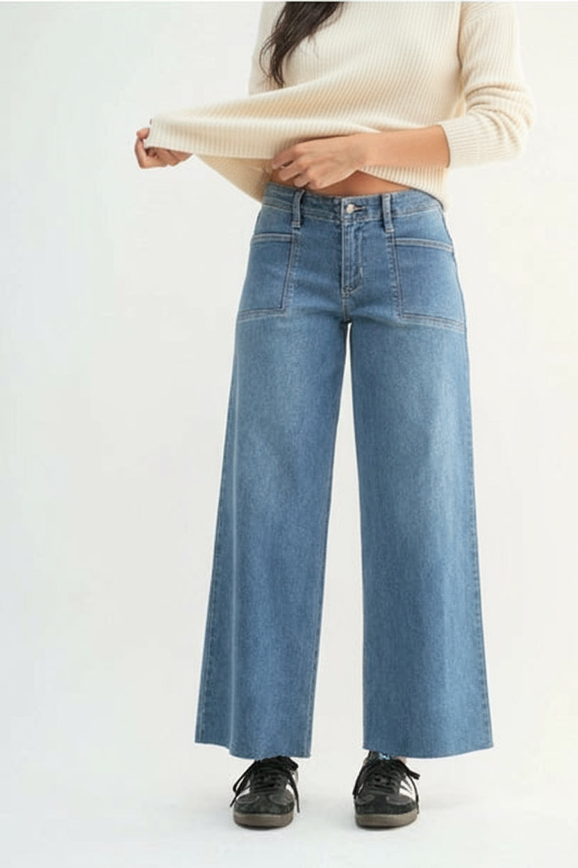 Woman wearing medium blue wide-leg jeans on a white background