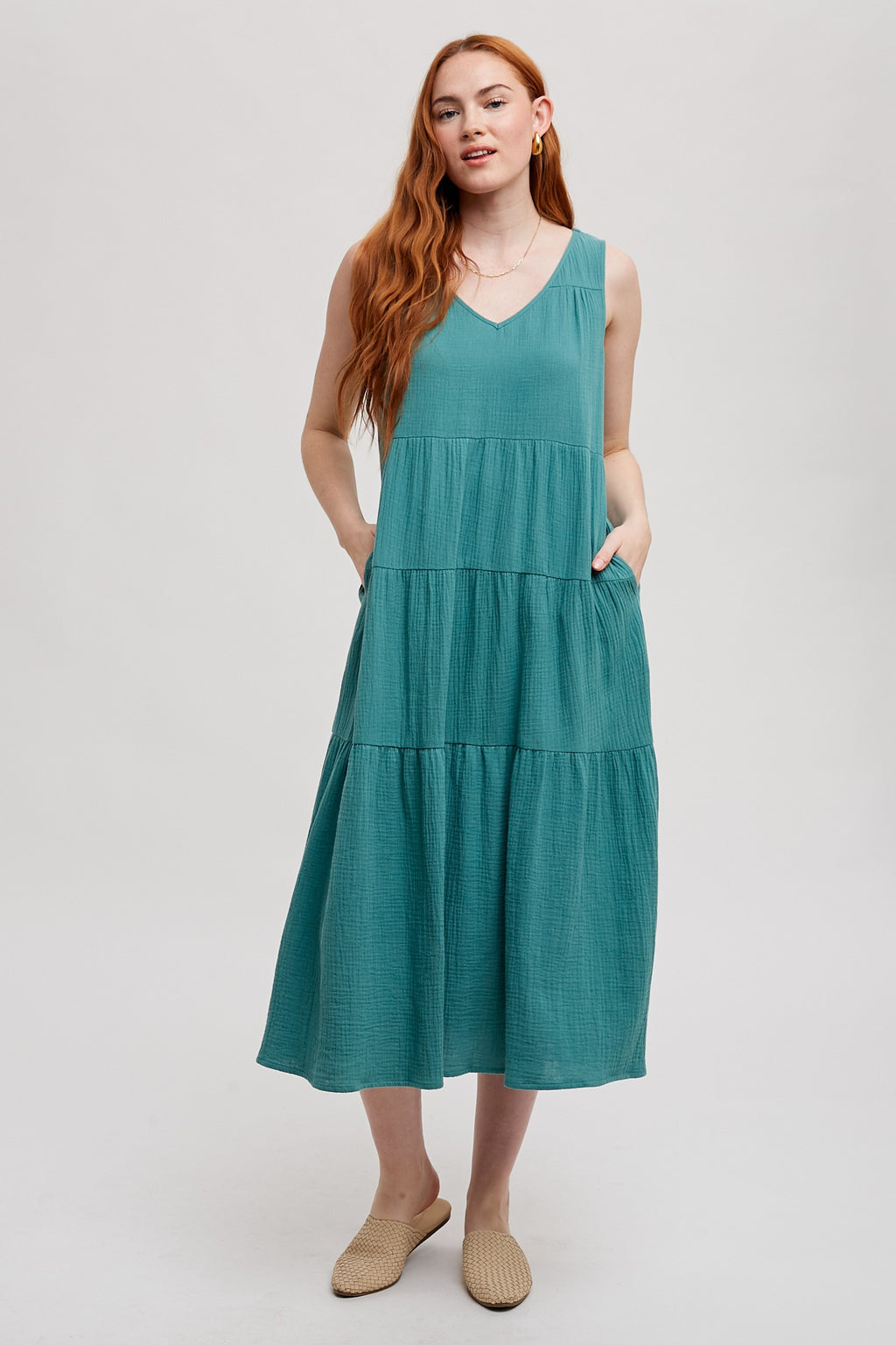 Woman wearing a sea green tank tiered dress on a white background