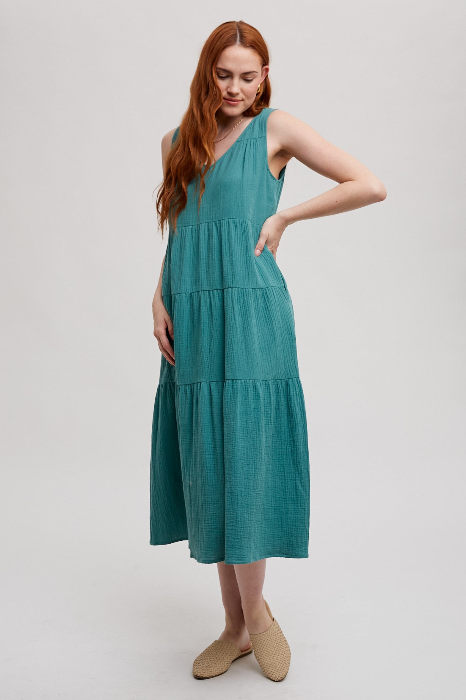 Woman wearing a sea green tank tiered dress on a white background