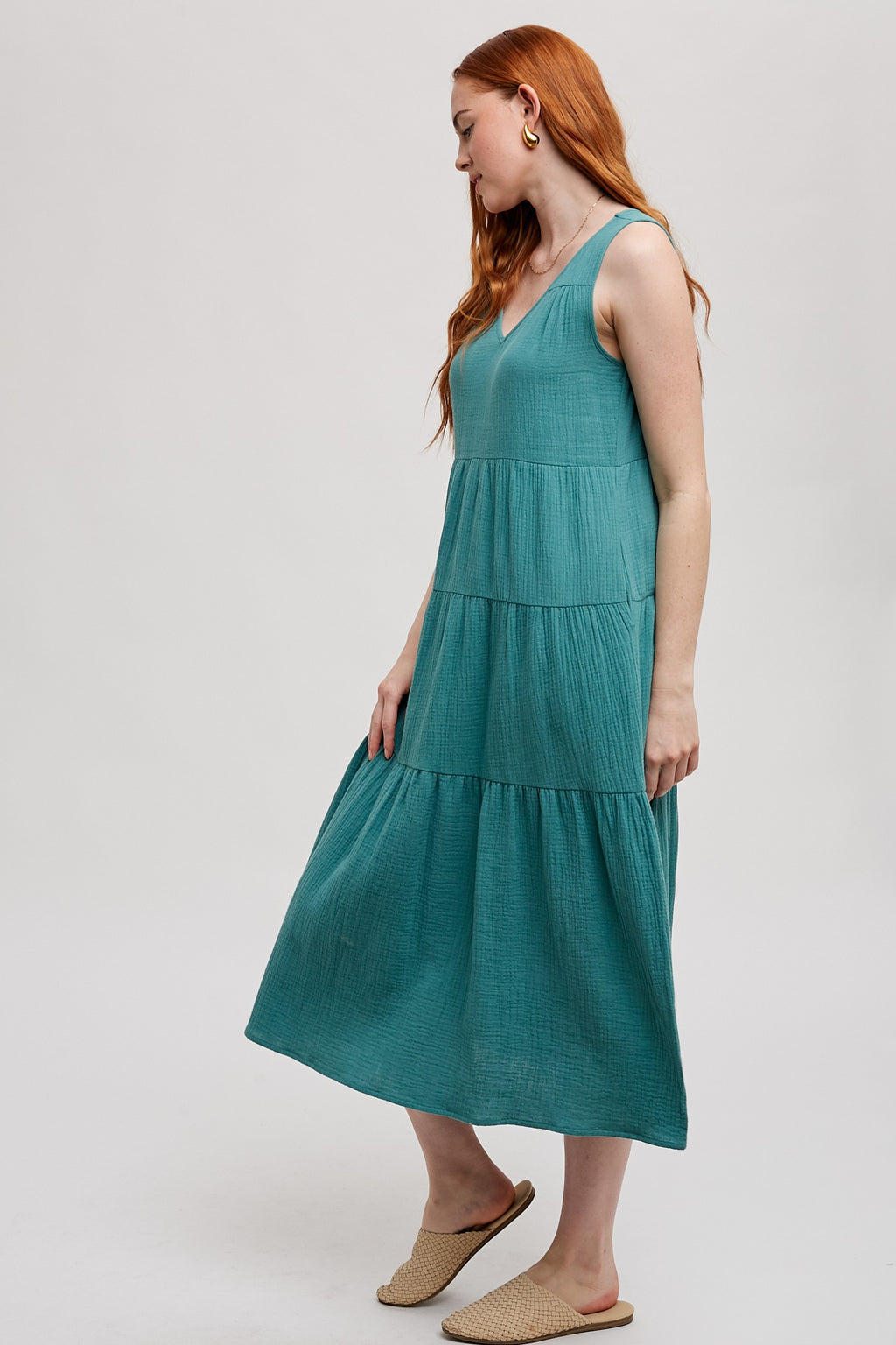 Woman wearing a sea green tank tiered dress on a white background