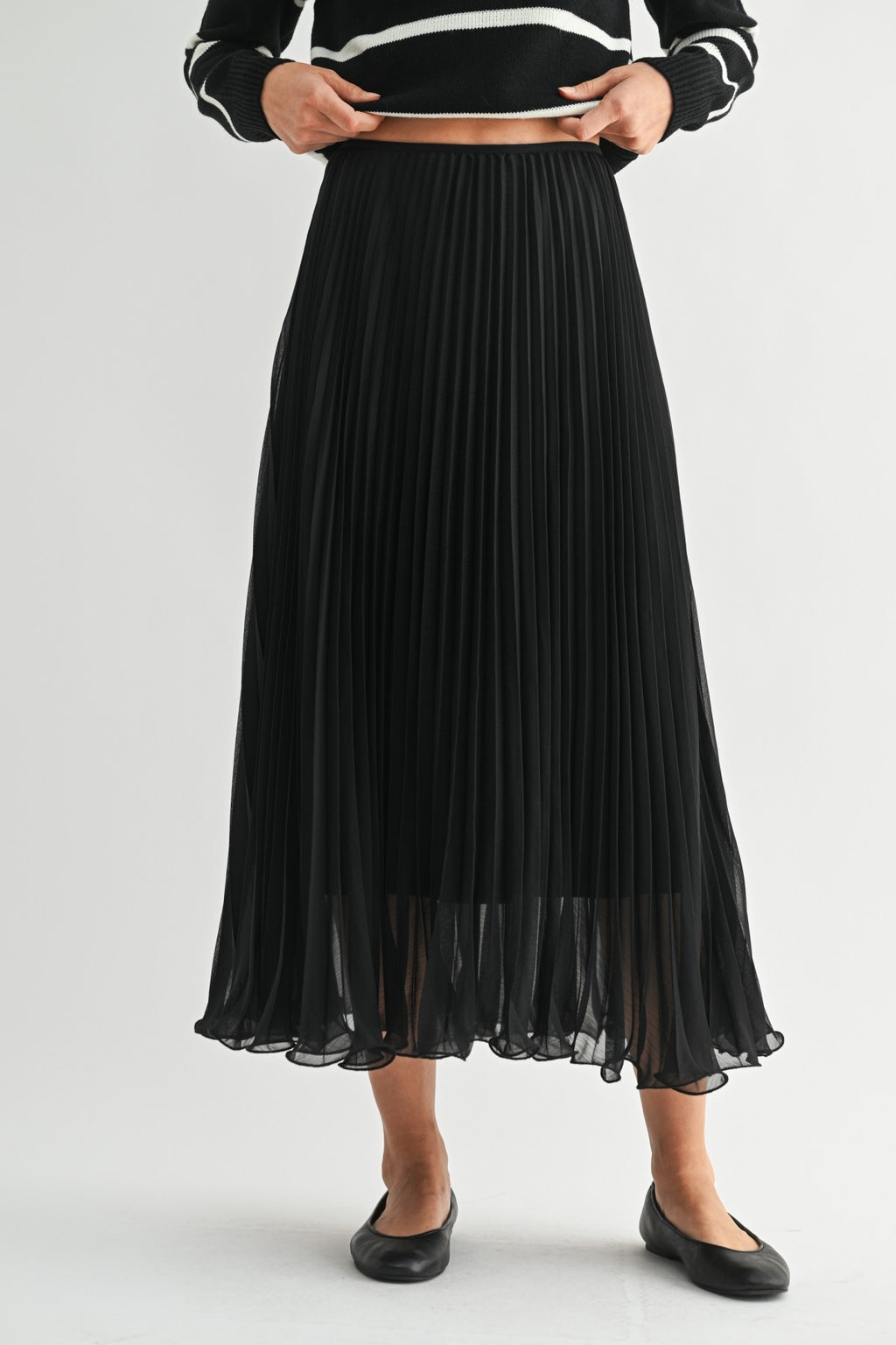 Woman wearing a black chiffon pleated midi skirt on a white background