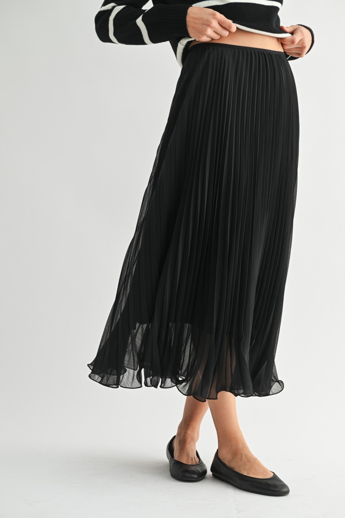 Woman wearing a black chiffon pleated midi skirt on a white background