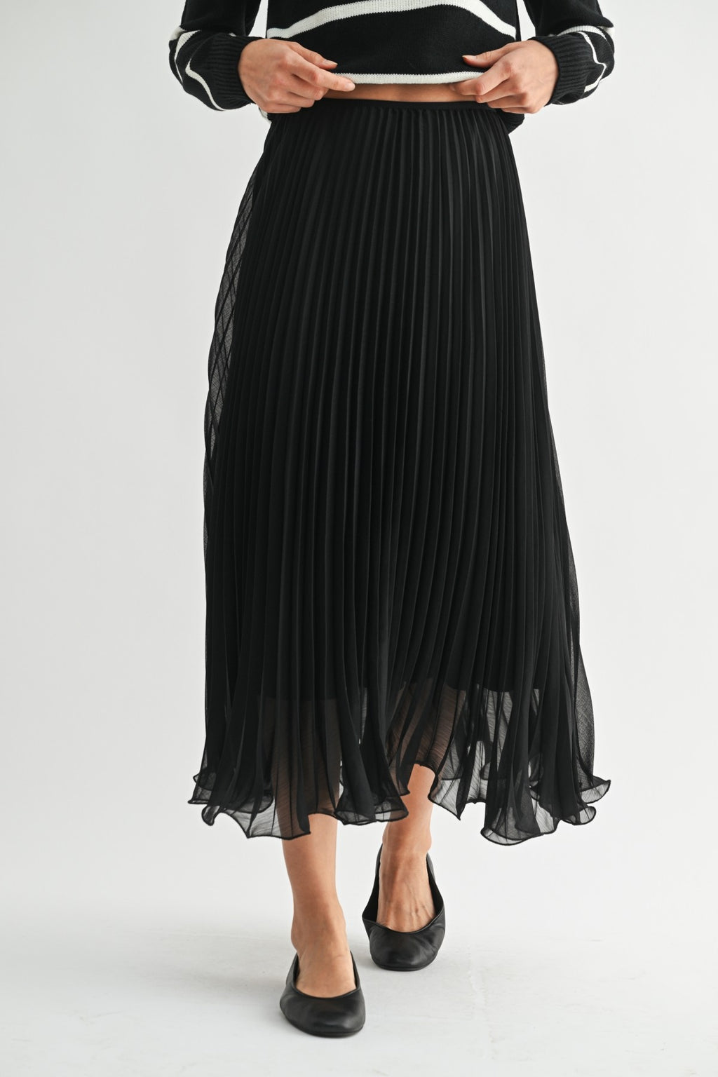 Woman wearing a black chiffon pleated midi skirt on a white background