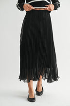 Woman wearing a black chiffon pleated midi skirt on a white background