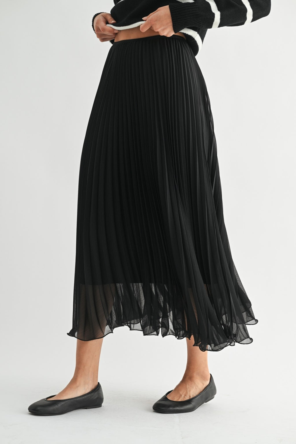Woman wearing a black chiffon pleated midi skirt on a white background