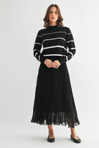 Woman wearing a black chiffon pleated midi skirt and sweater on a white background