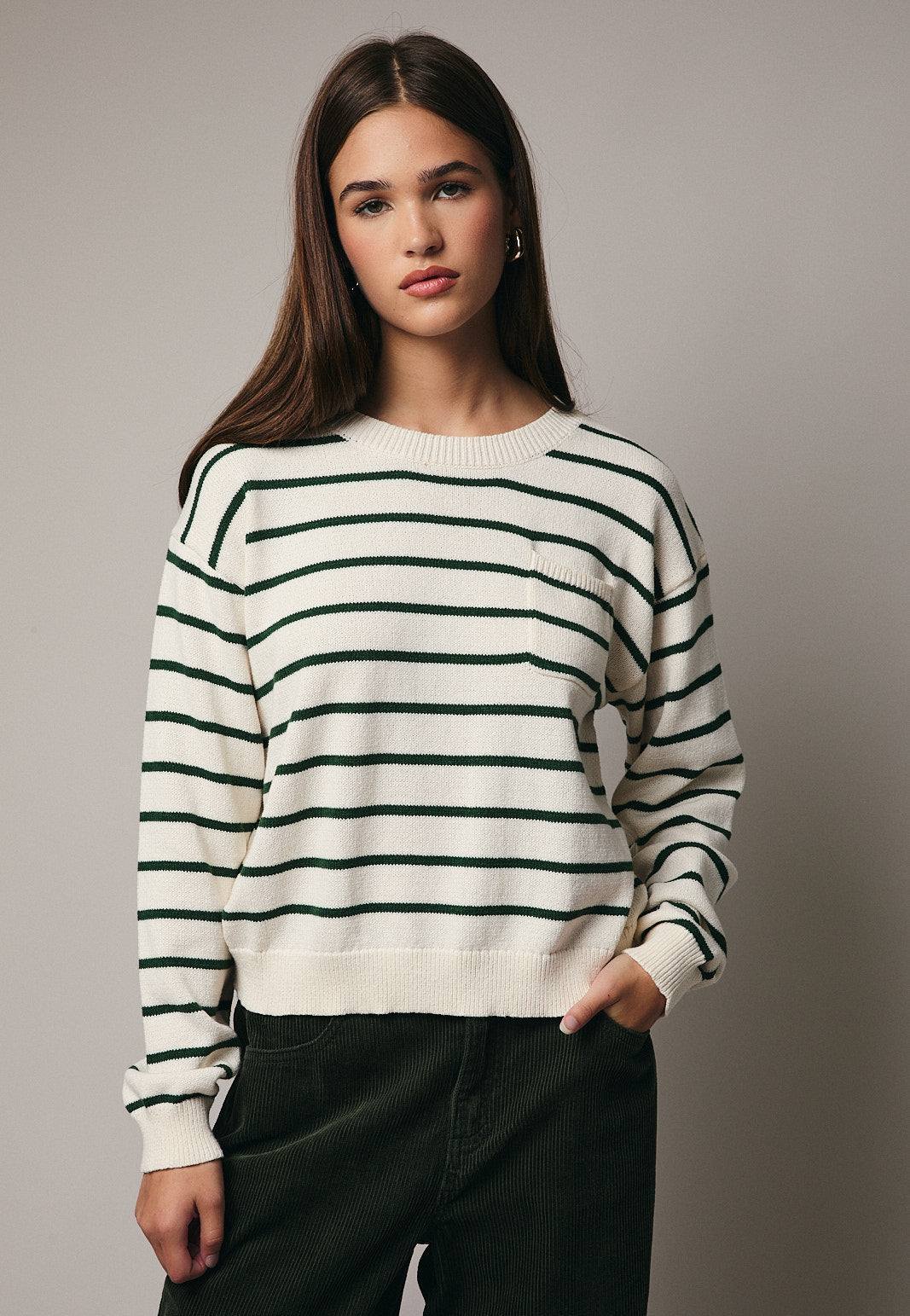 Woman wearing green and cream striped sweater on gray background