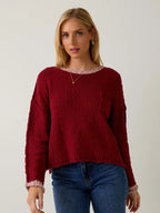 Woman wearing a berry sweater with cream contrast trim on a plain background