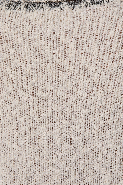 Close-up of a textured light grey knit with black contrast trim
