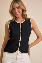 Woman wearing a black sleeveless  vest with white trim on a beige background